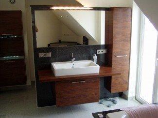 Waschtischschrank aus Holz an dunkler Steinwand